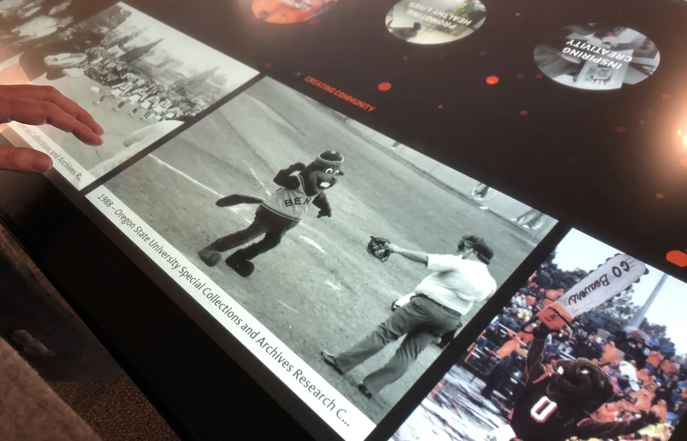 A story displayed on the OSU 150 touch table shows an old black-and-white photo of Benny the Beaver on a baseball field.