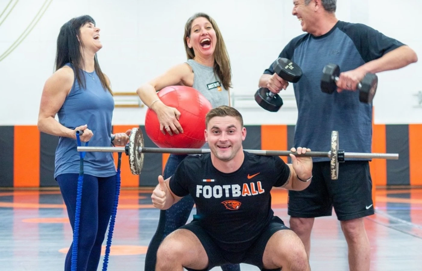 A laughing group of Faculty Staff Fitness instructors holding various types of gym equipment.