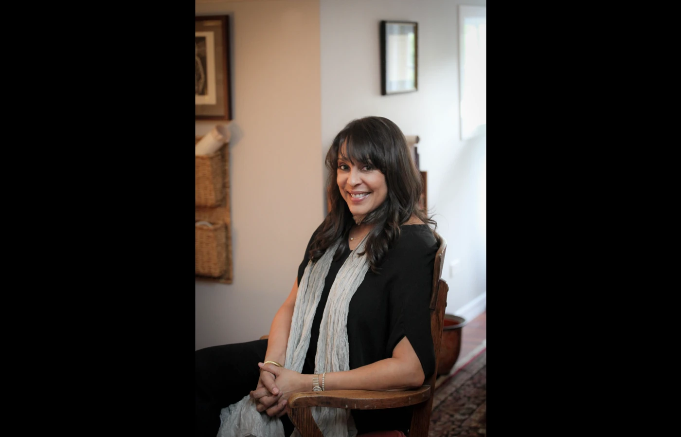 Poet Natasha Trethewey seated in a chair, wearing a long gray scarf and black dress.