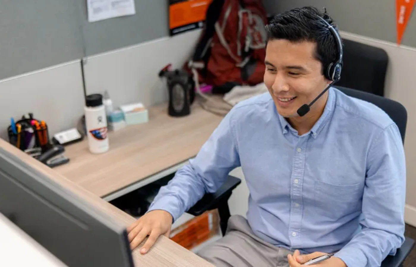 A man in a headset sits at a computer desk