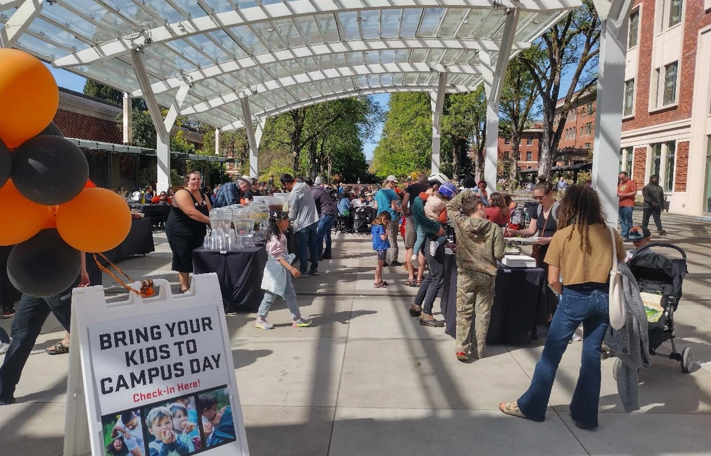 Orange and black balloons mark the entrance to the sunny and crowded SEC Plaza during Bring Your Kids to Campus Day.