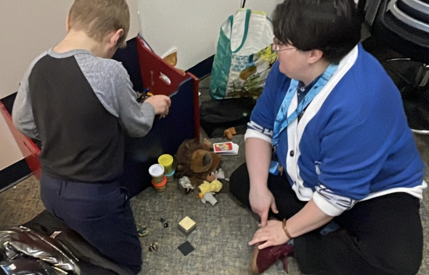 Child playing next to teacher