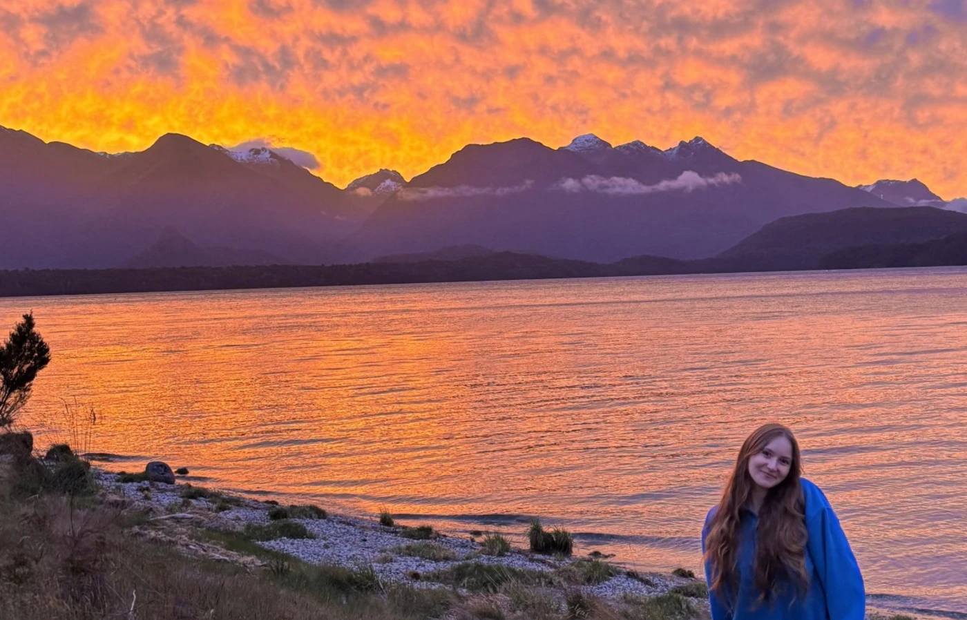 Sophia Jones in front of a brilliant sunset on a lake.
