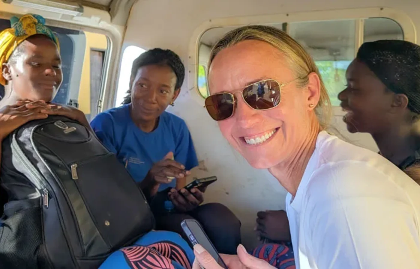 Liz Blanton smiling in a van with three other researchers in Zambia.