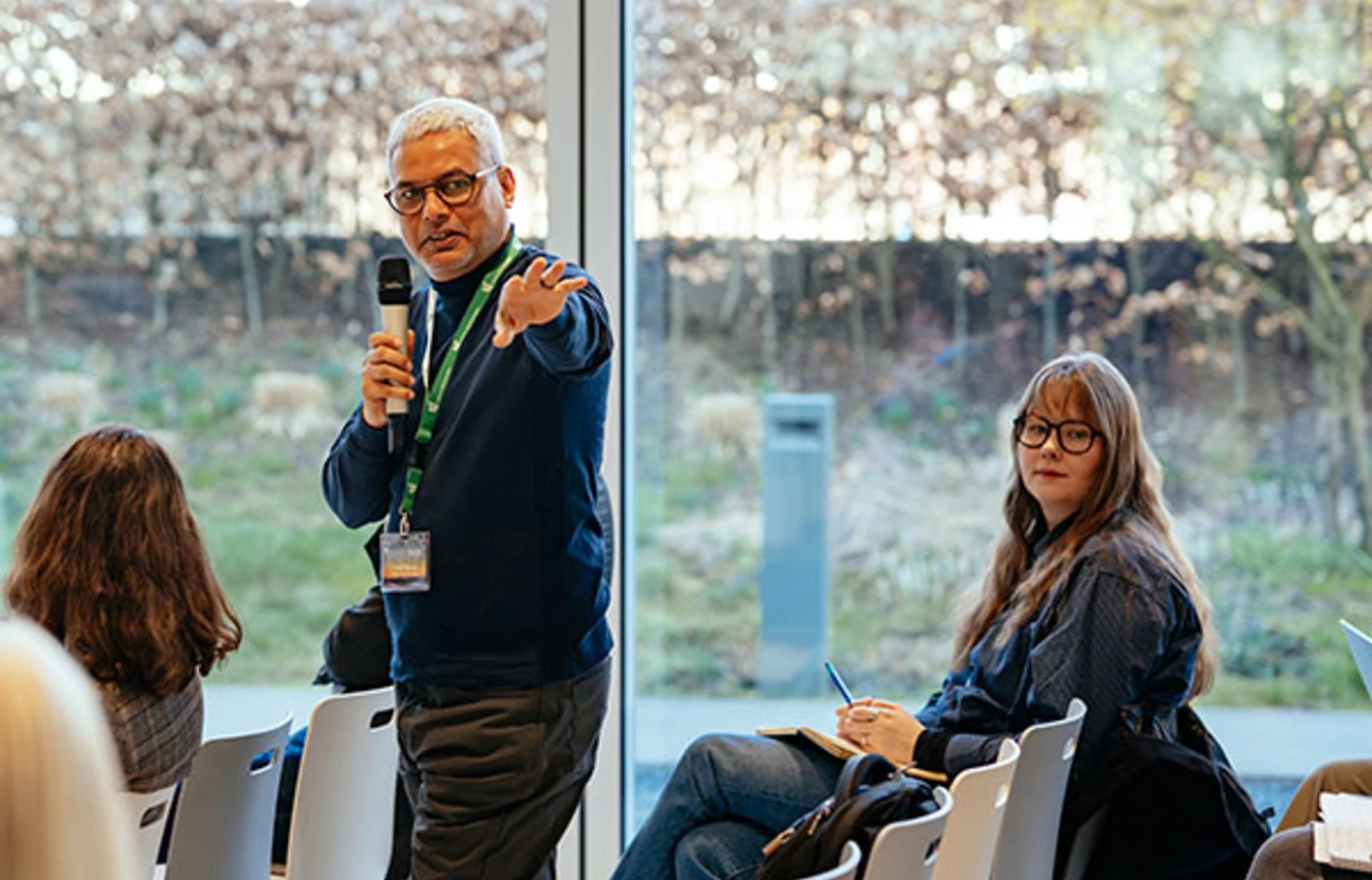 Rajat Panwar stands up in a row of chairs and addresses the room with a microphone.