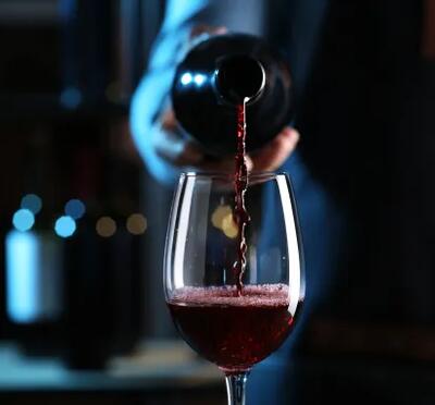 Dramatically lit wine bottle pouring red wine in a glass. 