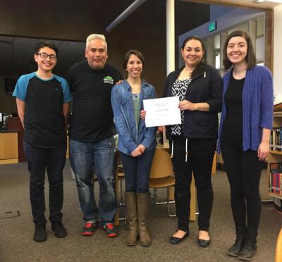 Yahir Santillan-Guzman (far left), then a student at The Dalles High School, received his Juntos program completion certificates from Andrea Flores (middle), with his parents and another Juntos volunteer present.
