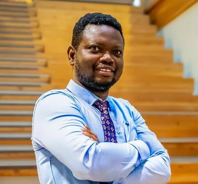 Sunday A. Adetunji, MD poses with his arms crossed, wearing a light blue collared shirt.