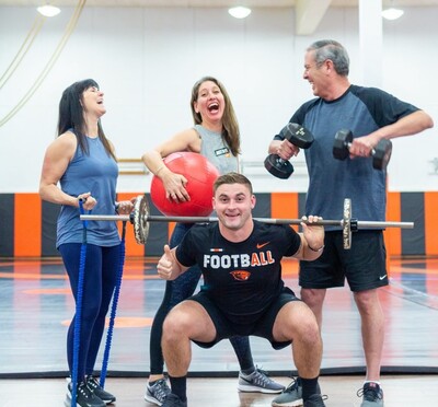 A laughing group of Faculty Staff Fitness instructors holding various types of gym equipment.