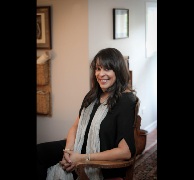 Poet Natasha Trethewey seated in a chair, wearing a long gray scarf and black dress.