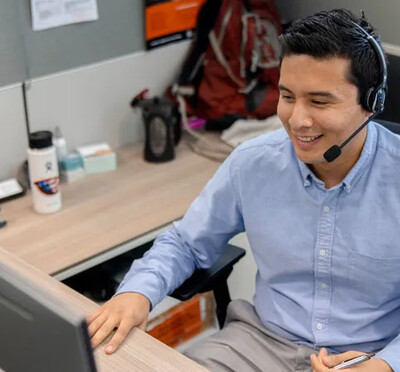 A man in a headset sits at a computer desk