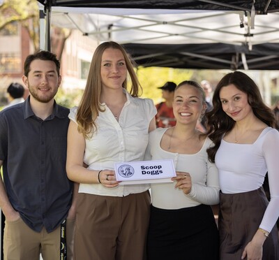 The four students on the Scoop Doggs team hold up their team sign.