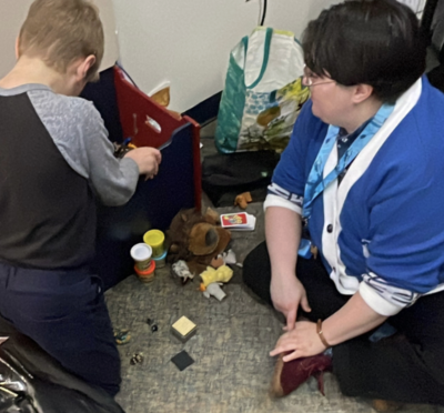 Child playing next to teacher