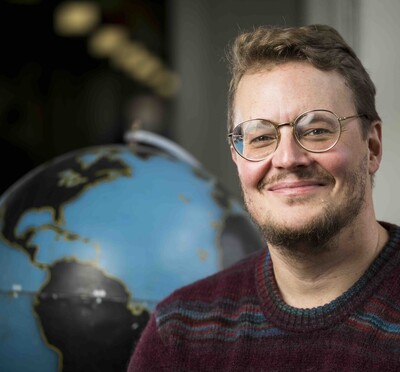 Jamon Van Den Hoek sits in front of a globe.
