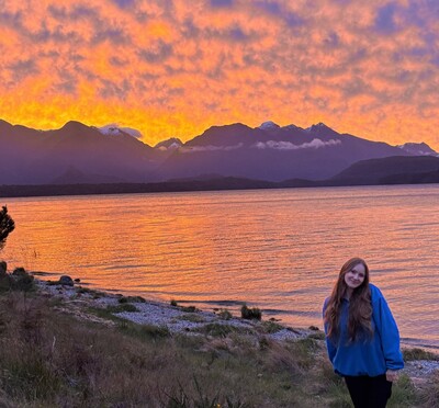 Sophia Jones in front of a brilliant sunset on a lake.