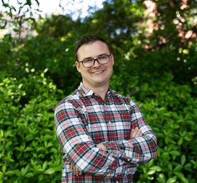 Warren Johnson posing in front of green foliage.