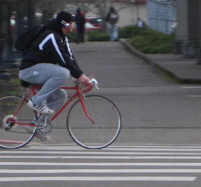 A student rides a red bike around campus.