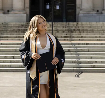 Kaitlyn Smith in her graduation stole and gown in front of the Memorial Union.