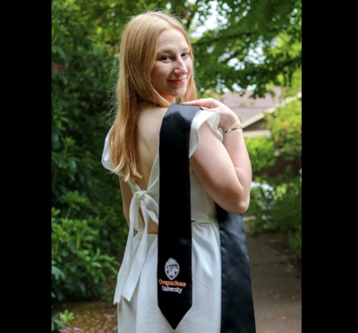 Lauren Damon wearing a white dress with her graduation stole over one shoulder