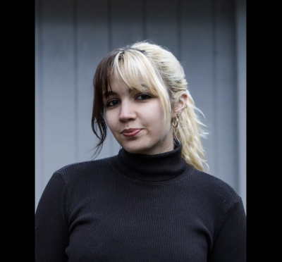 Morgan Barnaby with black-and-white hair in a black turtleneck.