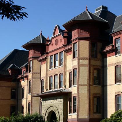 Stock image of Waldo Hall, where some OSU public health researchers have their offices; building is old-fashioned yellow brick with red at the top and black roofs on the spires.
