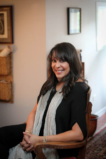 Poet Natasha Trethewey seated in a chair, wearing a long gray scarf and black dress.