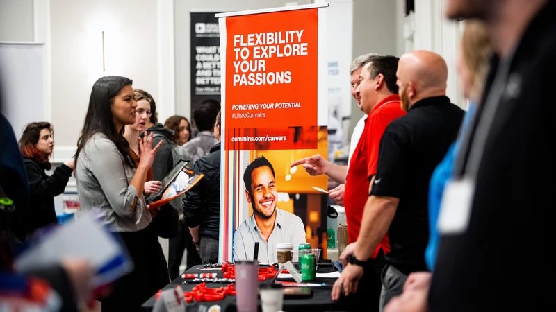 A busy career fair with students talking to recruiters over tabl