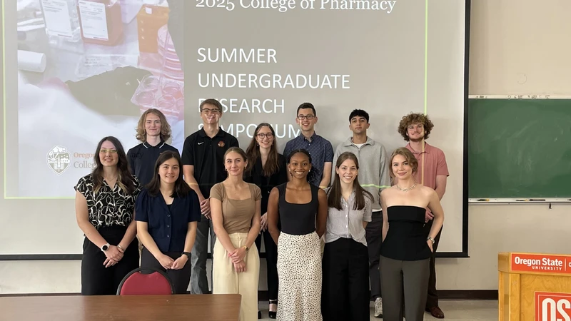 Undergraduate fellows from the College of Pharmacy's summer research fellowship pose together in the front of a classroom.