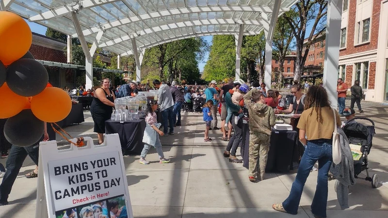 Orange and black balloons mark the entrance to the sunny and crowded SEC Plaza during Bring Your Kids to Campus Day.