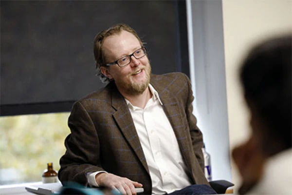Jim Thatcher sits wearing a brown blazer over a white collared shirt.