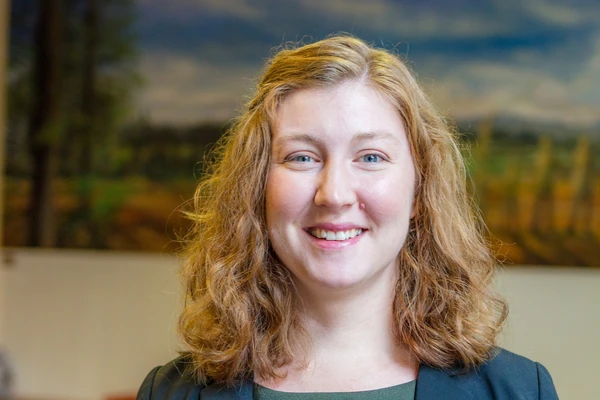 OSU child care researcher Megan Pratt smiles at the camera. She is a white woman with strawberry blonde hair, wearing a navy blazer.
