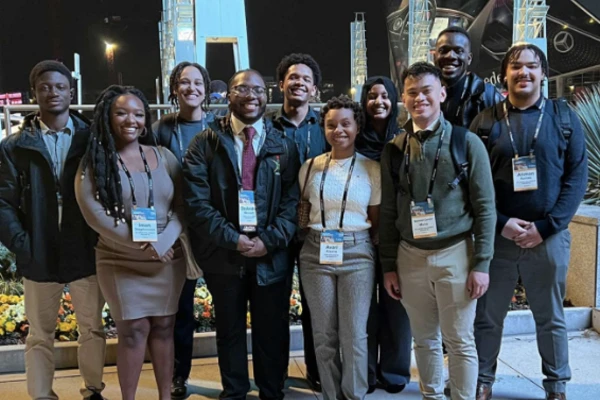 A group of a dozen Black engineering students pose together at a conference. 