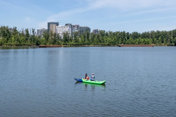 Two kayaks in the middle of a wide calm section of the Willamette River in Portland.