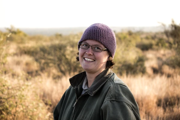 Researcher smiles while standing on the savannah.