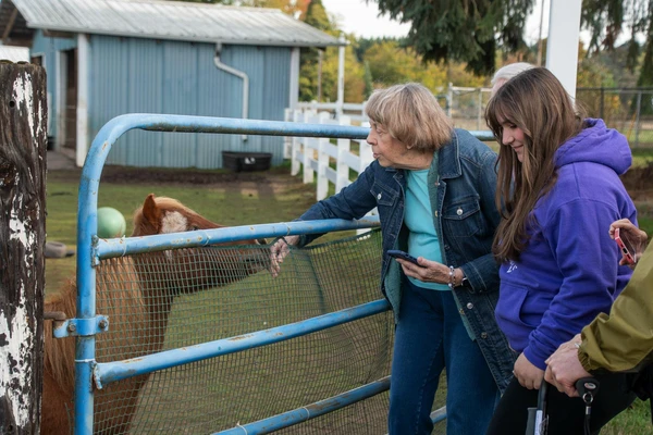 DJ, a miniature horse owned by Amy Hindman (far right) nuzzles the top of Marcia Perrolle's hand during a tour of the VFM Miniature Horse Farm by residents of The Springs at Sherwood.