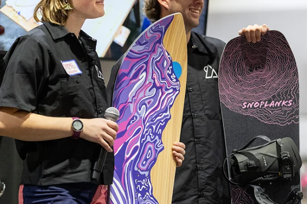 Two SnoPlanks students stand with colorful snowboards. 