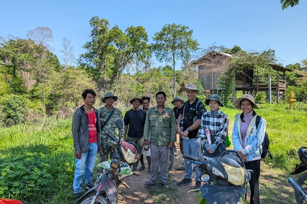 Researchers and community forest leaders in a group photo in front of some trees in Cambodia.