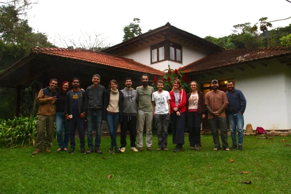 Group of people standing in front of a white building with red tile roof in Brazil.