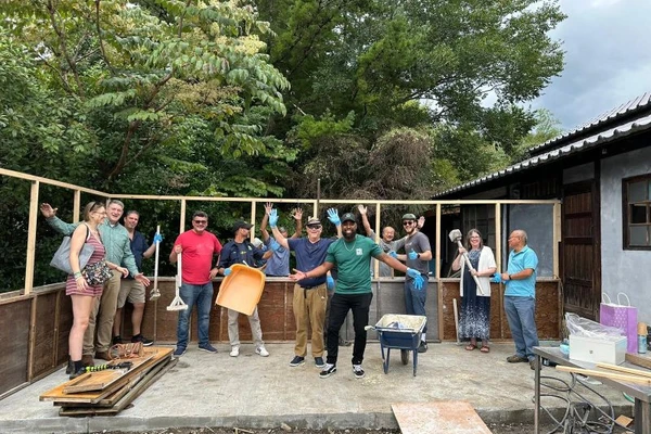 Group of people pose happily in front of a wall they're building in Japan, using hemp as insulation.