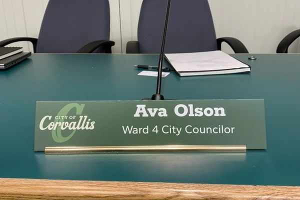 An official nameplate for Ava Olson, Ward 4 City Councilor, Corvallis, sits atop a desk.
