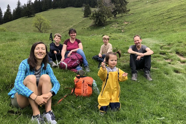 A group of people in colorful hiking clothes sit for a photo on a grassy hillside.