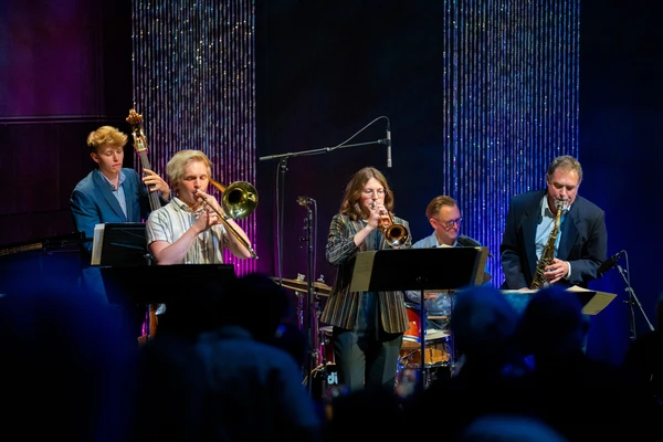 A five-piece band with upright bass, trombone, trumpet, saxophone and drums plays onstage at the PRAx kickoff event April 30, 2025.
