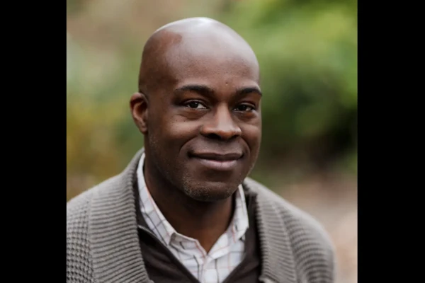 Cleavon Smith, bald Black man in gray cardigan and white collared shirt.