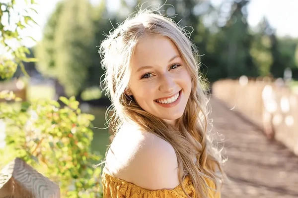 Portrait of Margaret Martin, smiling blonde girl in front of a vineyard.