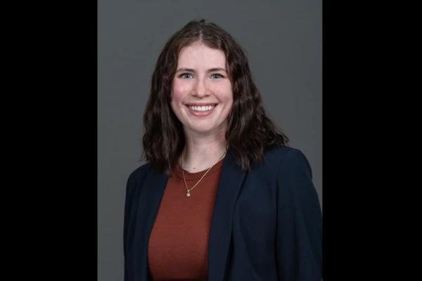 Headshot of Shayla Berrey, fair-skinned woman with dark curly hair, in a navy-blue blazer and red shirt.