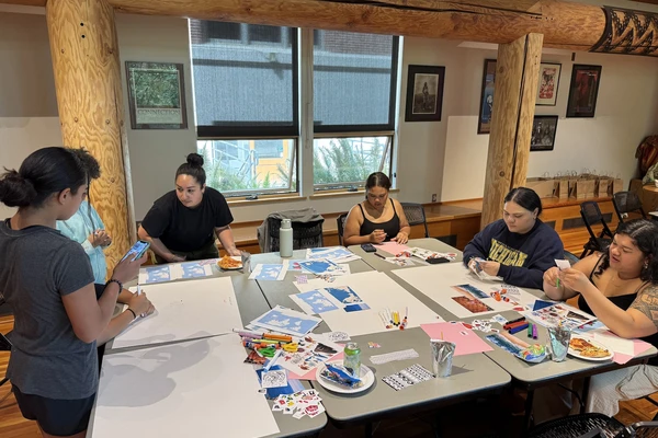 Half a dozen Pacific Islander students and community members make collages around a table.