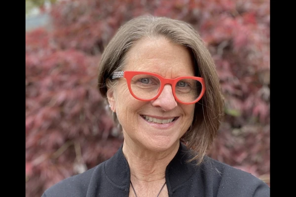 Headshot of Libby Ramirez outdoors, wearing bright orange glasses frames.