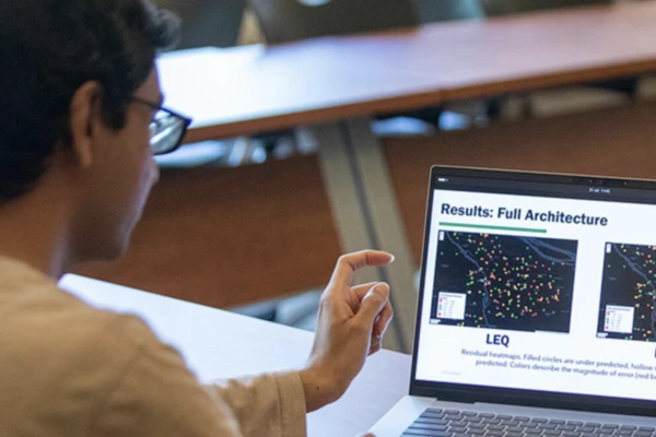 A master's student looks at an AI prediction model on a laptop.