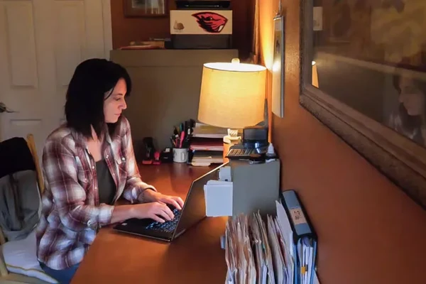 Lori Lerwill, fair-skinned woman with short dark hair, working on her laptop at a desk.