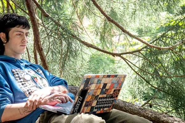 Graduate sitting under cedar tree